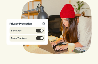 Une femme avec un bonnet rouge qui travaille sur un ordinateur portable avec les options « Bloquer les publicités » et « Bloquer les traceurs » activées dans « Protection de la vie privée ».